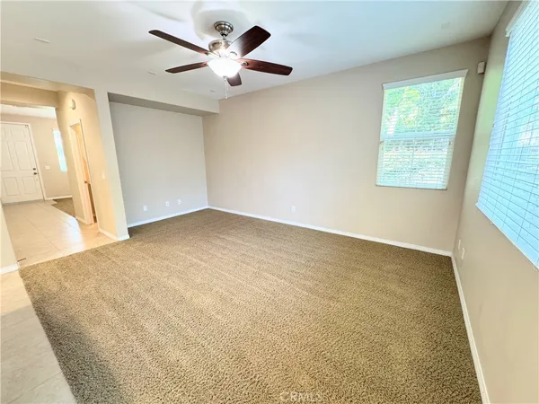 an empty room with a window and a chandelier fan