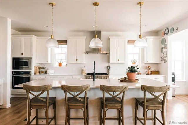 a kitchen with stainless steel appliances granite countertop a dining table chairs and white cabinets