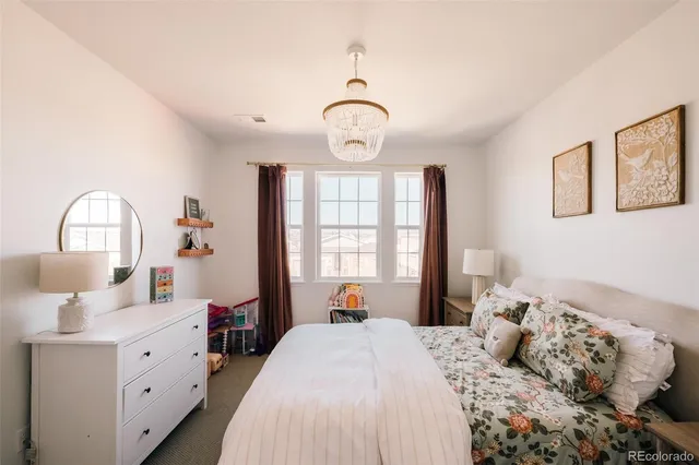 a bedroom with bed window and a chandelier