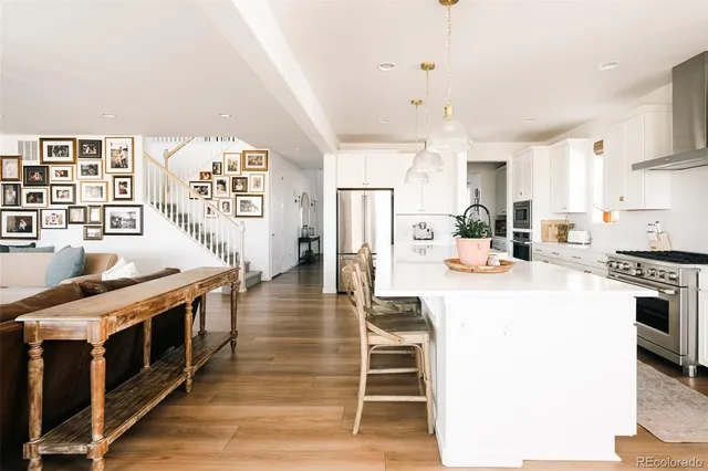 a kitchen with stainless steel appliances kitchen island granite countertop a stove a sink dishwasher and a refrigerator with wooden floor