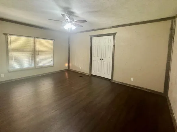 an empty room with wooden floor and windows with curtains