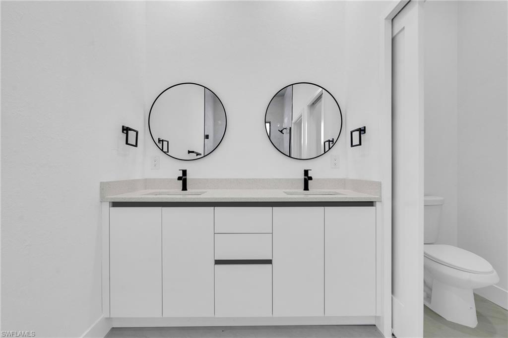 406 West 11th Street Lehigh Acres, FL 33972 - Photo 18 of 24 a bathroom with a double vanity sink and a toilet