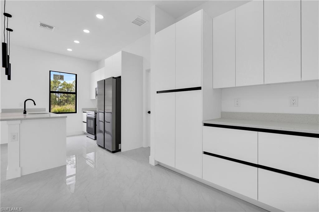 406 West 11th Street Lehigh Acres, FL 33972 - Photo 6 of 24 a kitchen with stainless steel appliances a refrigerator sink and cabinets