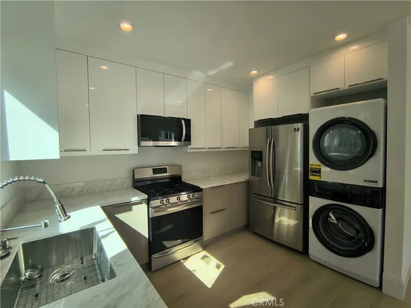 a kitchen with stainless steel appliances granite countertop a sink a stove a washer and dryer