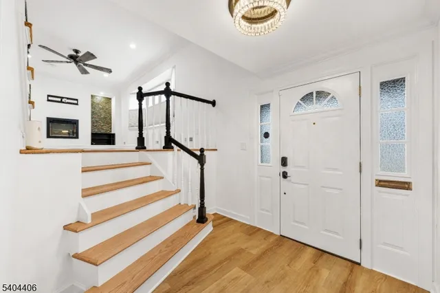 a view of a livingroom with a fireplace a ceiling fan and wooden floor