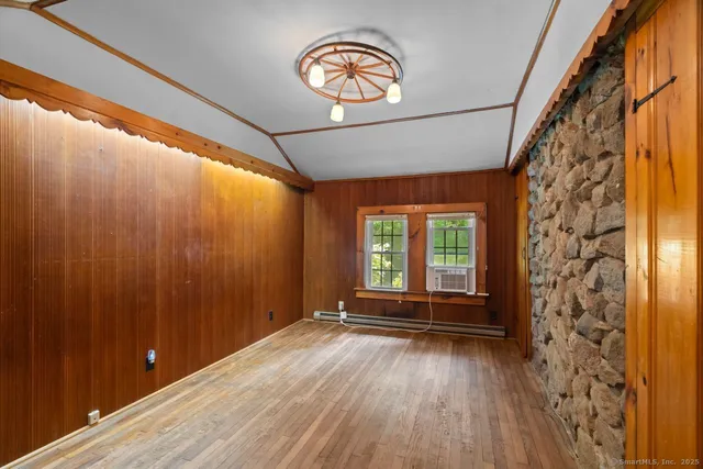 a view of an empty room with a window and wooden floor