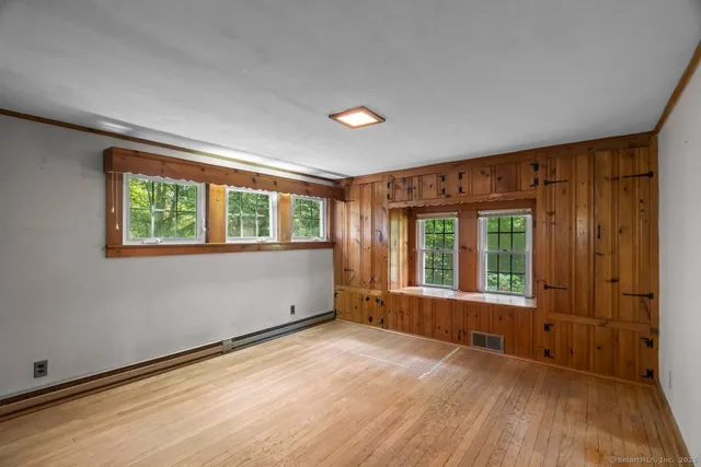 an empty room with wooden floor and windows