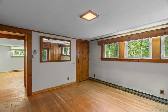 a view of empty room with wooden floor and fan