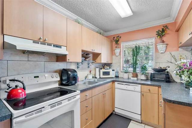 a kitchen with kitchen island granite countertop a sink stainless steel appliances cabinets and a potted plant