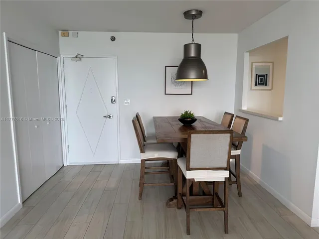 a dining room with wooden floor a chandelier a wooden table and chairs