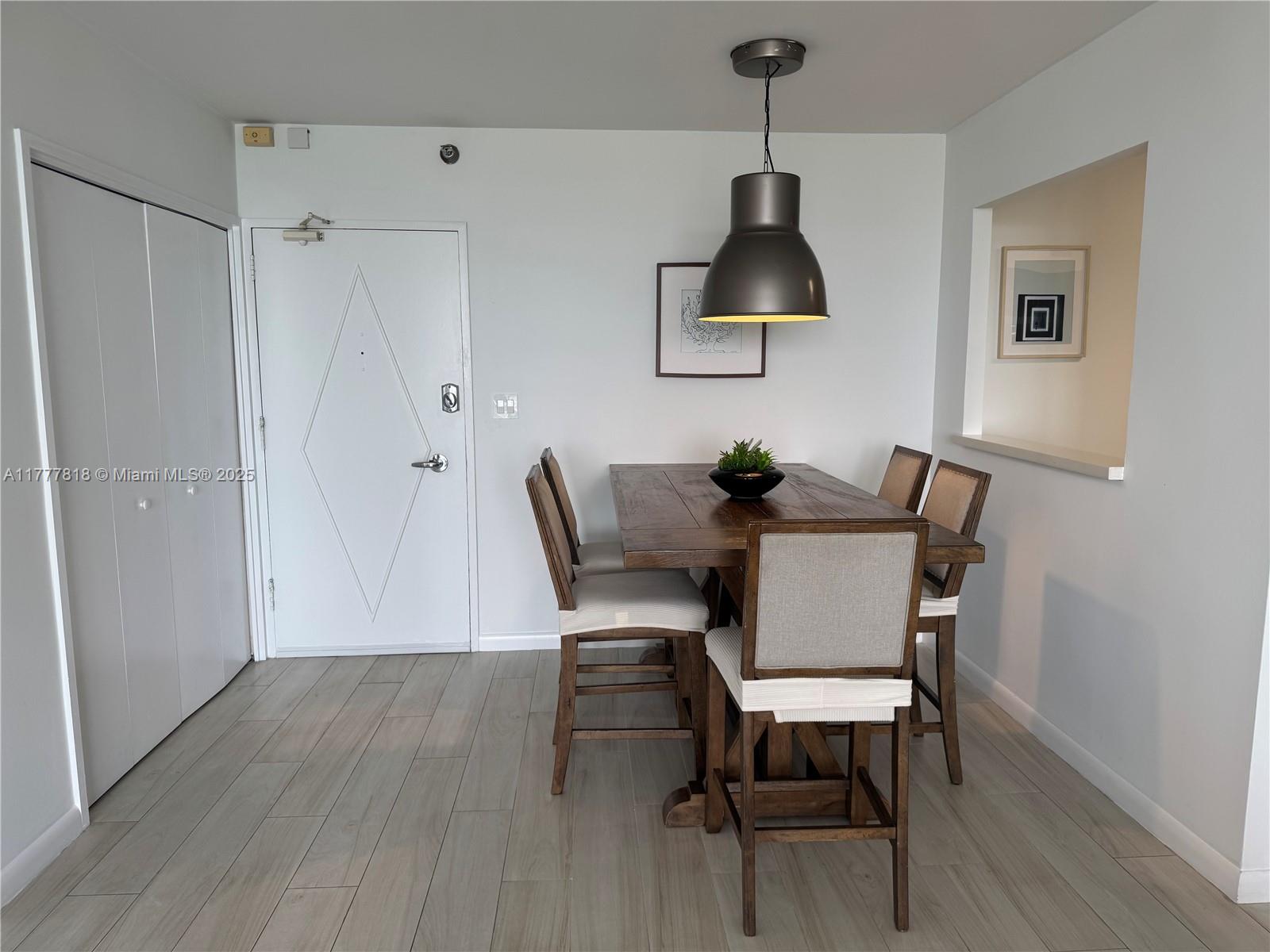 5161 Collins Avenue, Unit 1206 Miami Beach, FL 33140 - Photo 6 of 28 a dining room with wooden floor a chandelier a wooden table and chairs