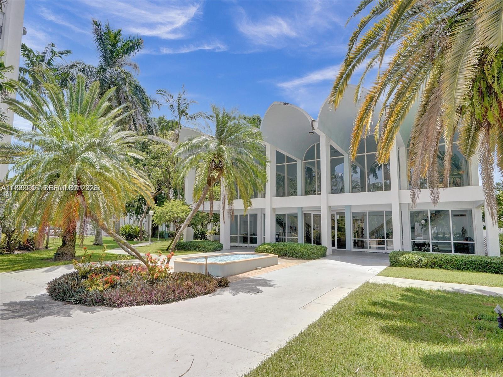 496 Northwest 165th Street, Unit D310 Miami, FL 33169 - Photo 16 of 16 a front view of a building with a garden