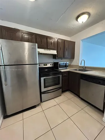 a kitchen with stainless steel appliances granite countertop a refrigerator a sink a stove a microwave and a counter top