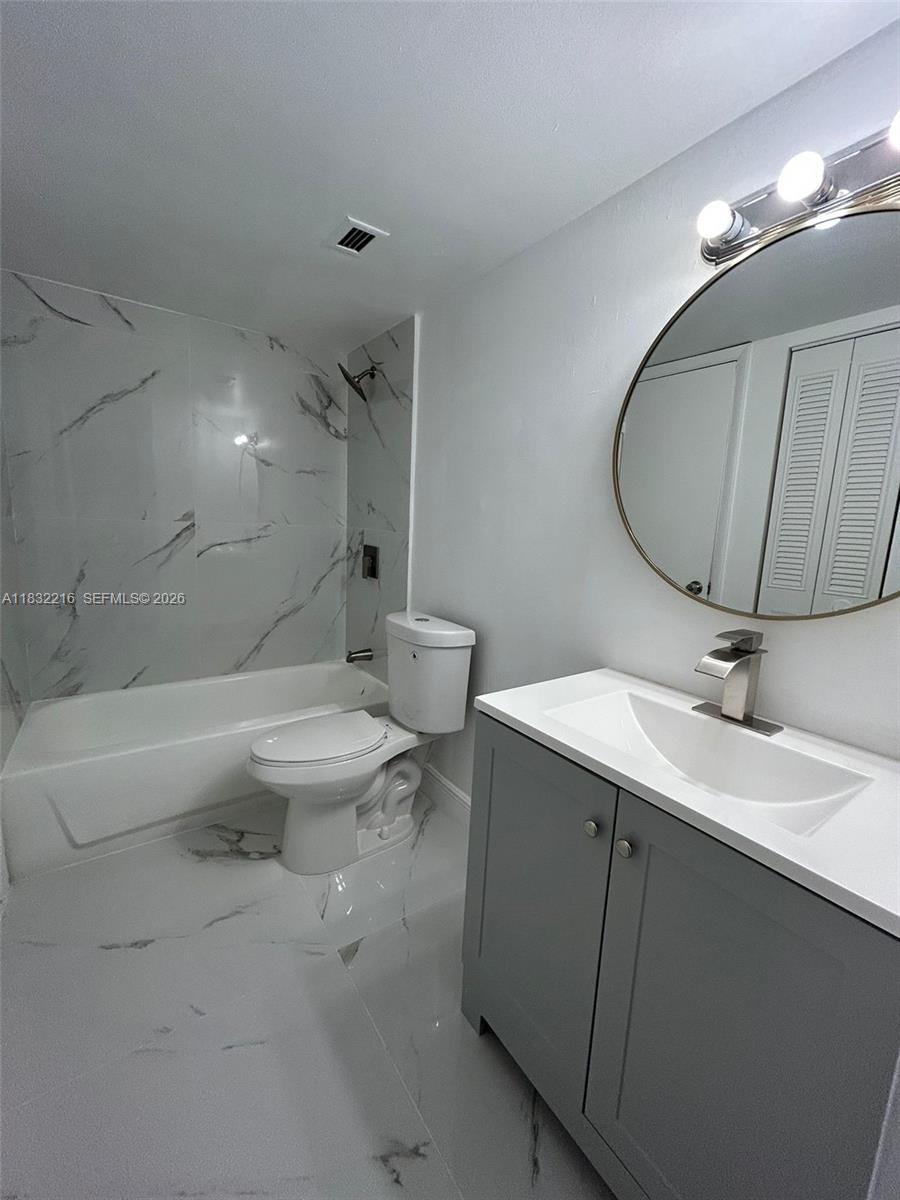 496 Northwest 165th Street, Unit D310 Miami, FL 33169 - Photo 5 of 16 a bathroom with a toilet a sink and mirror