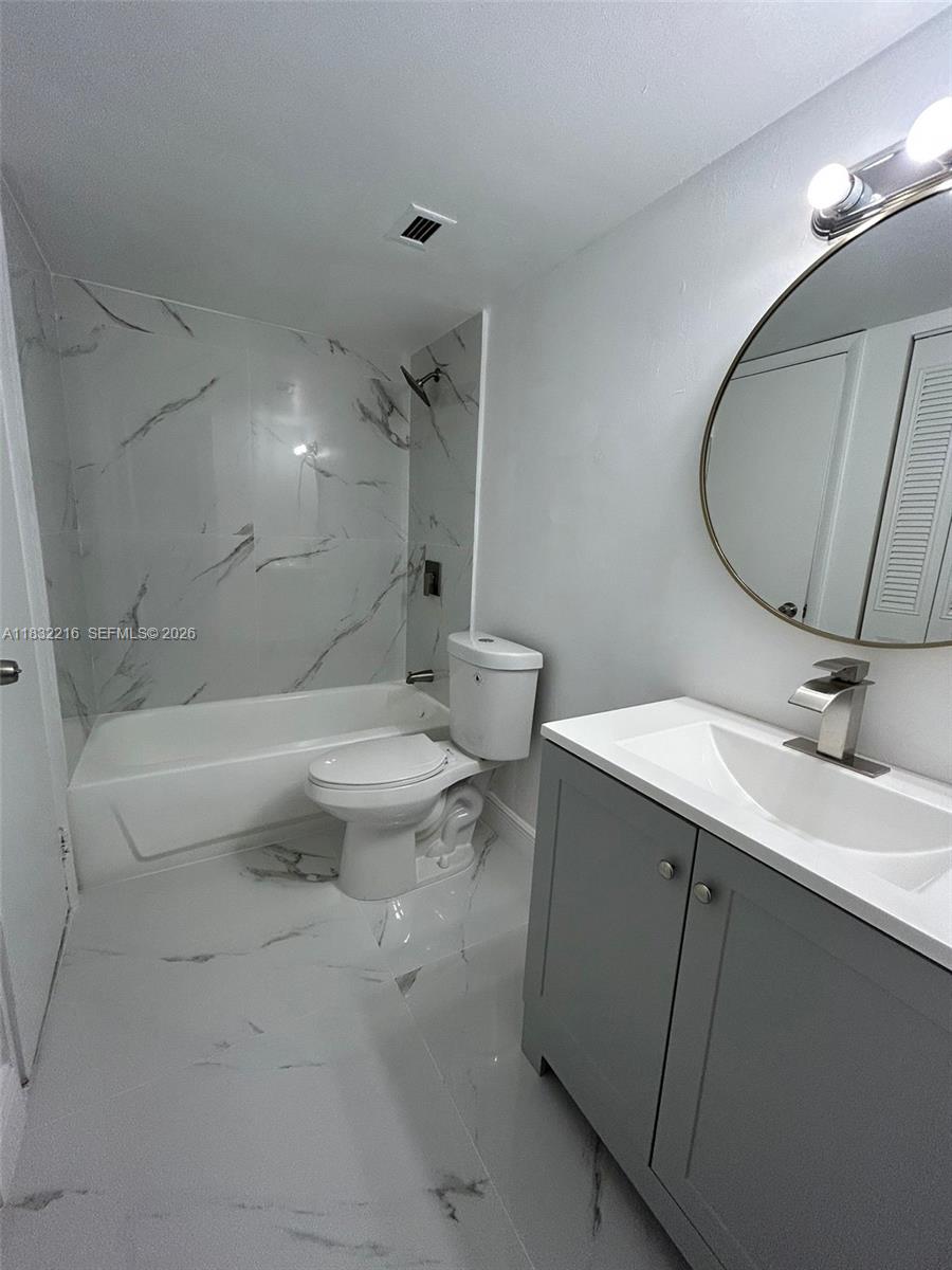 496 Northwest 165th Street, Unit D310 Miami, FL 33169 - Photo 8 of 16 a bathroom with a sink a toilet and a mirror