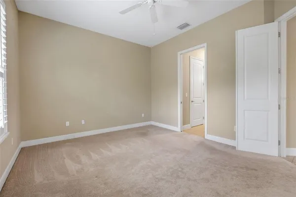 an empty room with windows and fan