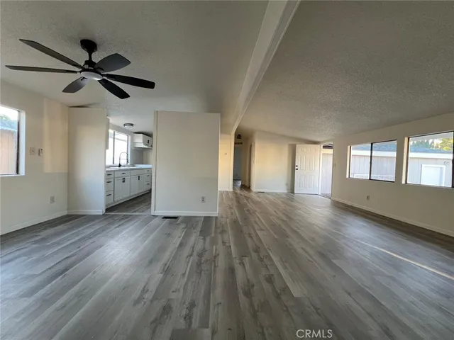 an empty room with wooden floor fan and windows