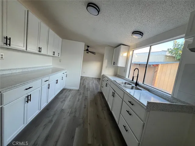 a large kitchen with granite countertop a large window and white cabinets