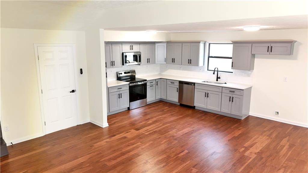 5257 Post Ridge Court Stone Mountain, GA 30088 - Photo 11 of 42 a large kitchen with cabinets wooden floor and stainless steel appliances