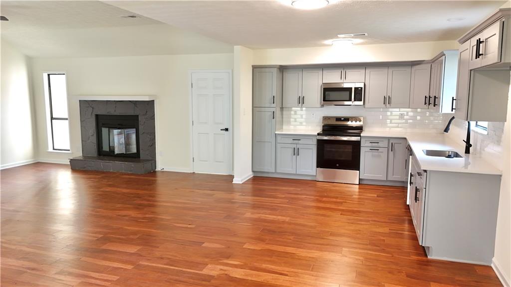 5257 Post Ridge Court Stone Mountain, GA 30088 - Photo 13 of 42 a large kitchen with stainless steel appliances granite countertop a stove top oven a sink dishwasher and a refrigerator with wooden floor