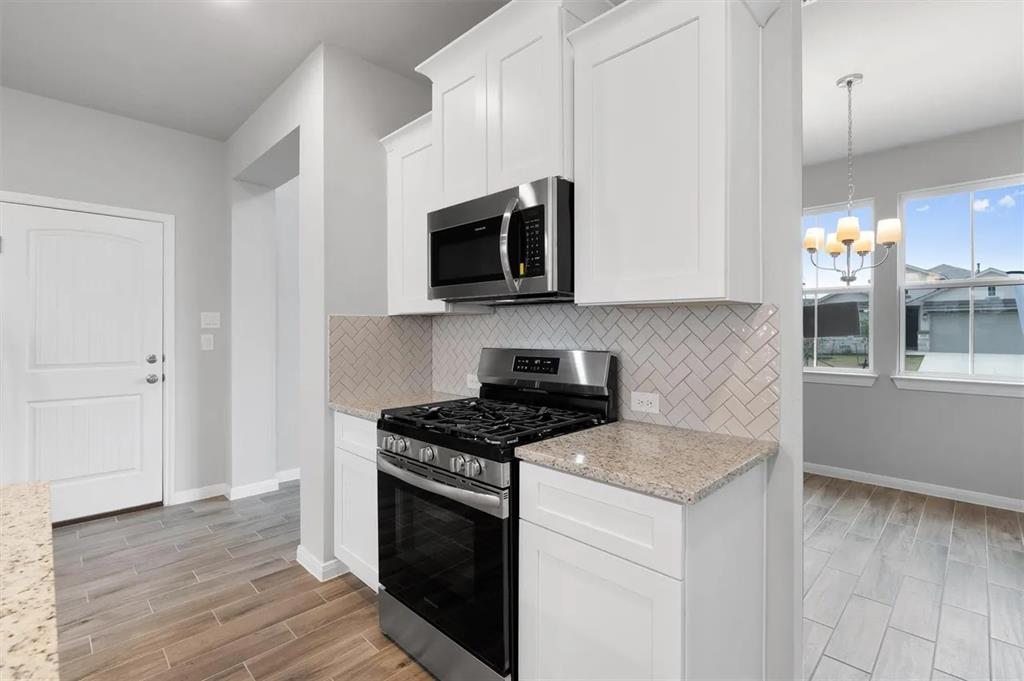 332 Stellar Wind Drive Georgetown, TX 78628 - Photo 13 of 29 A contemporary kitchen space boasts stainless steel appliances, white cabinetry, and durable tile flooring.
