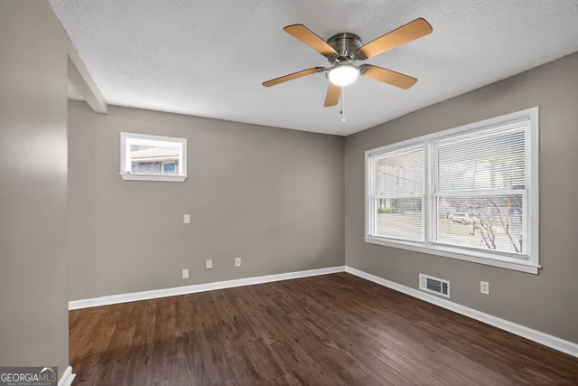 an empty room with wooden floor and windows