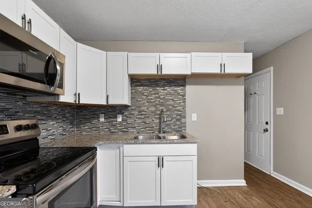 a kitchen with stainless steel appliances a sink dishwasher stove microwave and cabinets