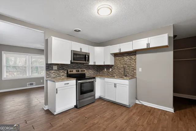 a kitchen with stainless steel appliances granite countertop a stove top oven a sink and a microwave