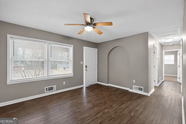 a view of an empty room with wooden floor and a window