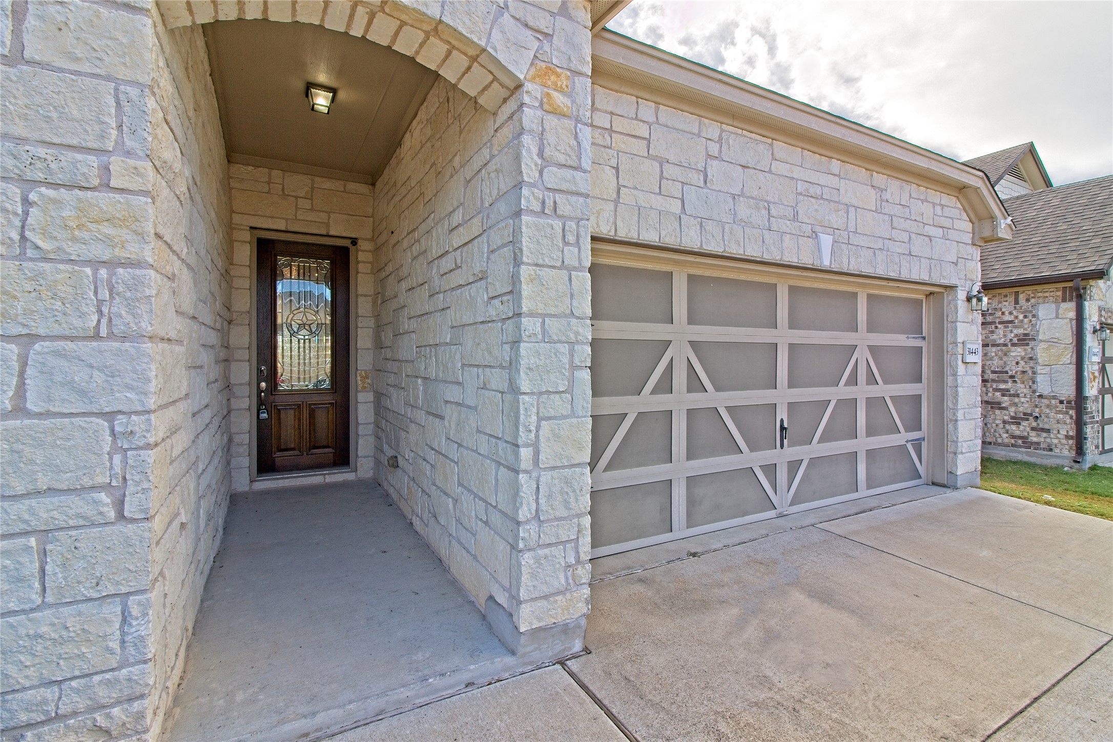 31443 Kingsway Road Georgetown, TX 78628 - Photo 4 of 40 A welcoming stone facade with an arched entry and a functional garage.