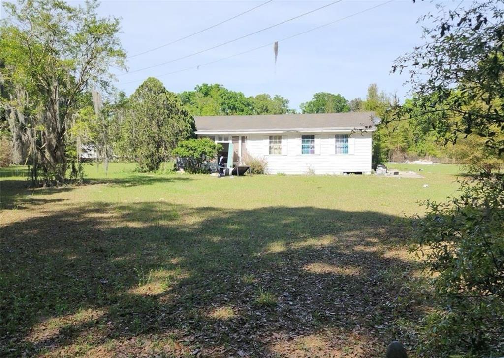 a view of a big house with a big yard and large trees