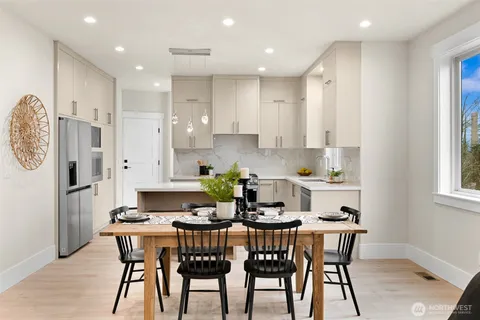 a kitchen with stainless steel appliances kitchen island granite countertop a dining table chairs and a refrigerator