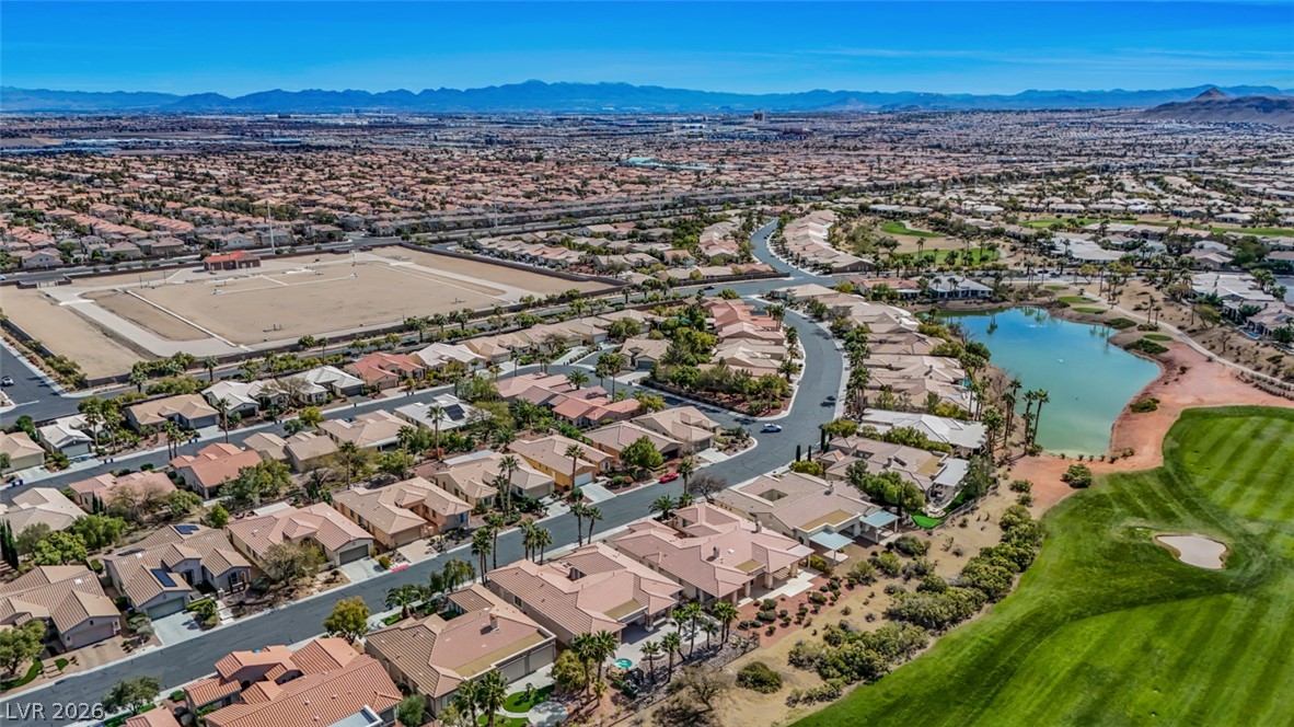 5015 Rivedro Street Las Vegas, NV 89135 - Photo 83 of 91 An aerial perspective reveals a vast community, featuring numerous residential homes, a sparkling lake, and a verdant golf course under a clear sky.