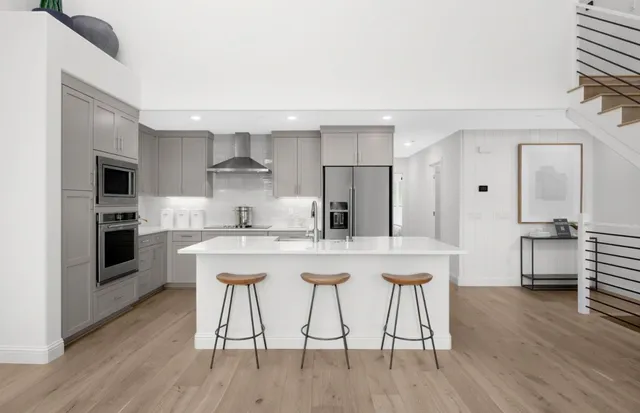 a kitchen with stainless steel appliances granite countertop a stove a sink dishwasher and a refrigerator with wooden floor