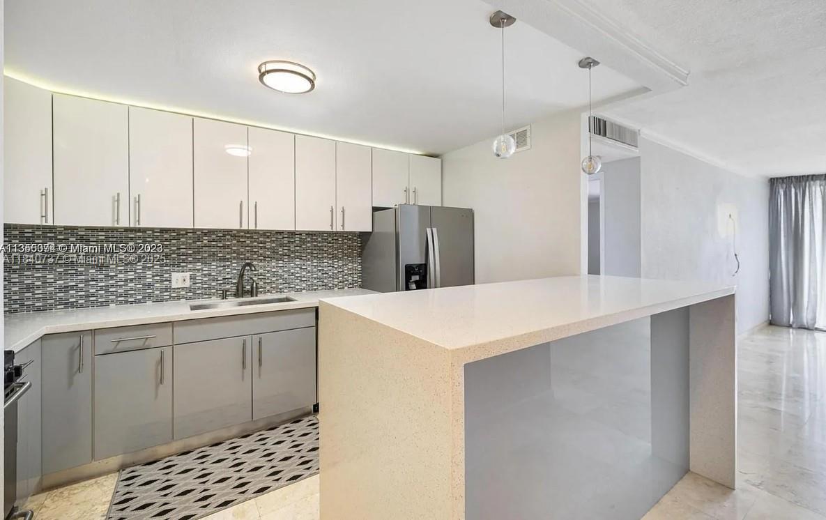 a kitchen with stainless steel appliances a sink a refrigerator and wooden cabinets