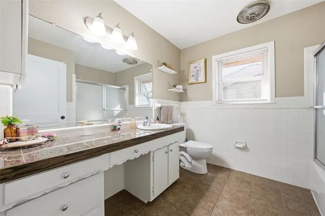 a bathroom with a granite countertop sink a toilet and a mirror