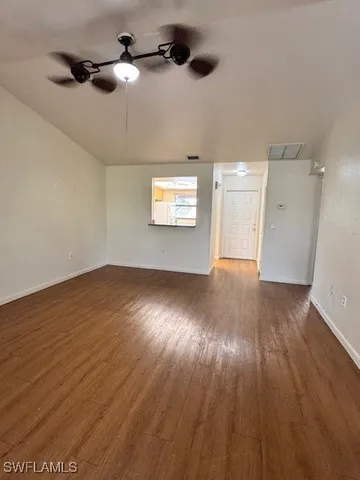 an empty room with wooden floor cabinet and windows