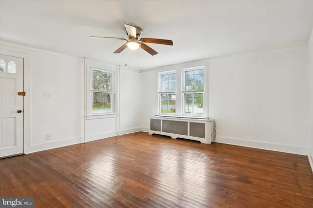 a view of an empty room with a window and wooden floor