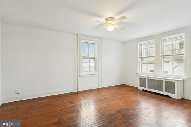 an empty room with wooden floor chandelier fan and windows