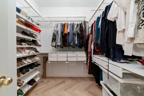 a view of walk in closet with clothes and shoes