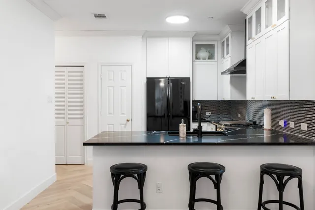 a kitchen with stainless steel appliances granite countertop a table chairs in it and wooden floors