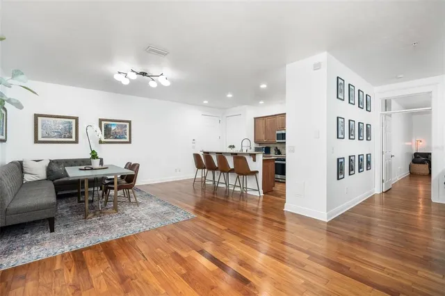 a living room with furniture and a dining table with wooden floor
