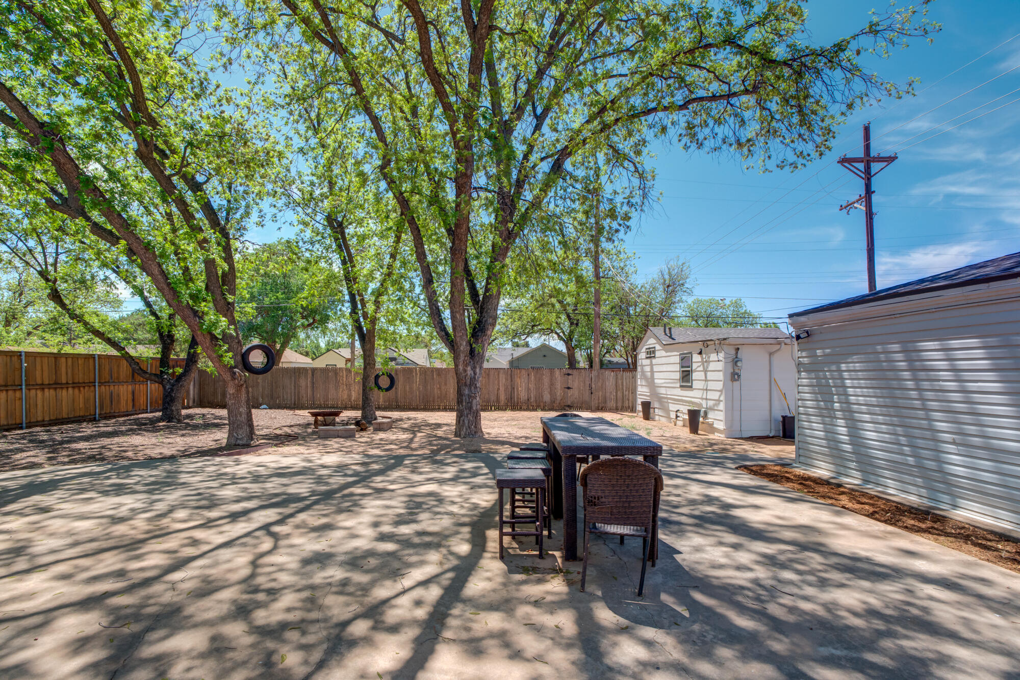 2629 24th Street Lubbock, TX 79410 - Photo 22 of 28 a view of a backyard with table and chairs and a barbeque with wooden fence and plants