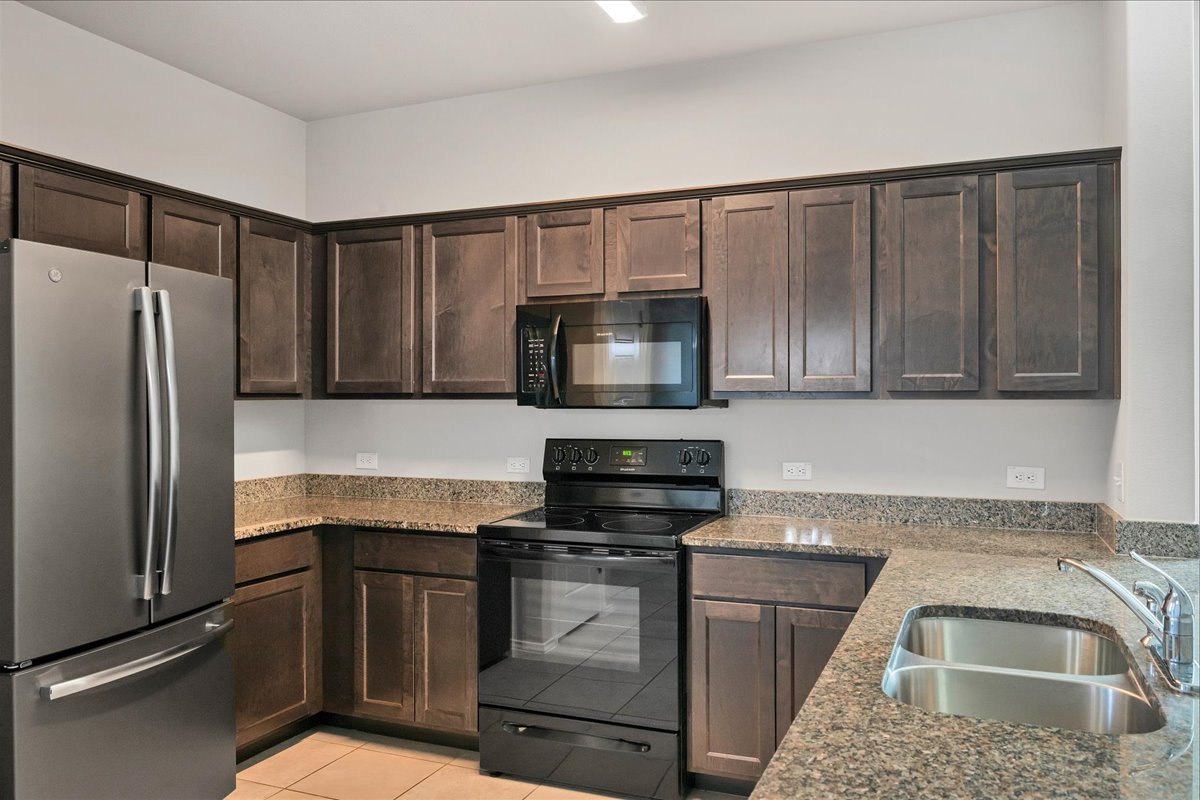 1202 Garland Road Georgetown, TX 78626 - Photo 13 of 28 Kitchen featuring dark wood-finish cabinetry, granite-style countertops, and a full suite of black and stainless steel appliances, including a French door refrigerator, range, and built-in microwave