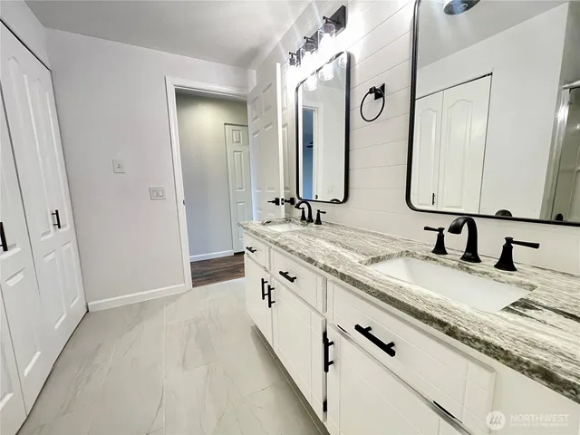 a bathroom with a granite countertop double vanity sink and a mirror