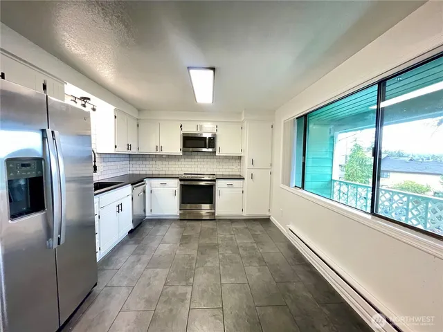 a large kitchen with a large window and stainless steel appliances