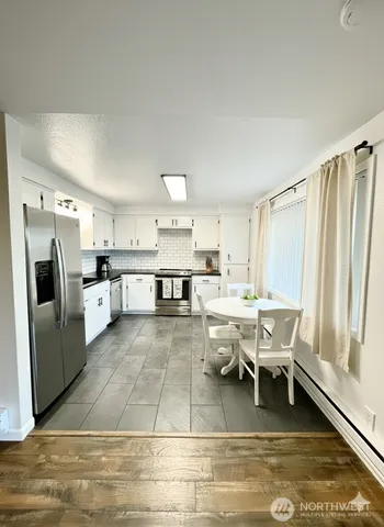 a large kitchen with a table chairs refrigerator and a window