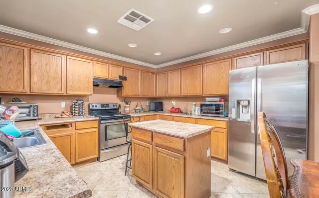 a kitchen with stainless steel appliances granite countertop a sink stove refrigerator and cabinets
