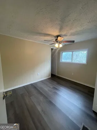 an empty room with wooden floor fan and windows