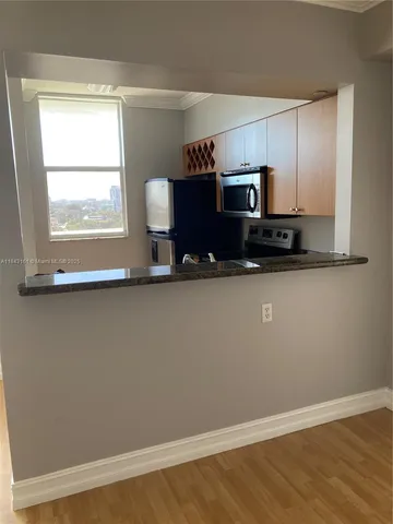 a kitchen with granite countertop a stove a microwave a sink and a refrigerator